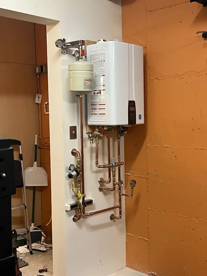 Plumbing technician inspecting water heater connections in Raymondville